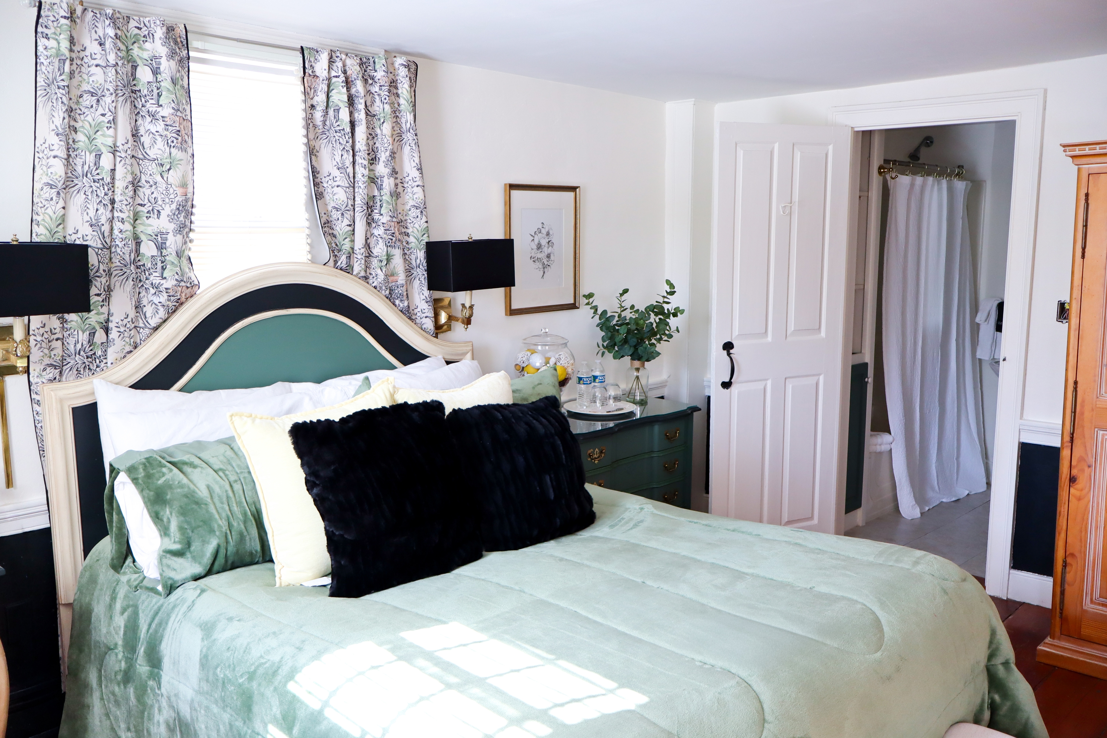 A small, charming bathroom featuring a pedestal sink with gold fixtures, a tub/shower combo, and built-in shelving with flowers.