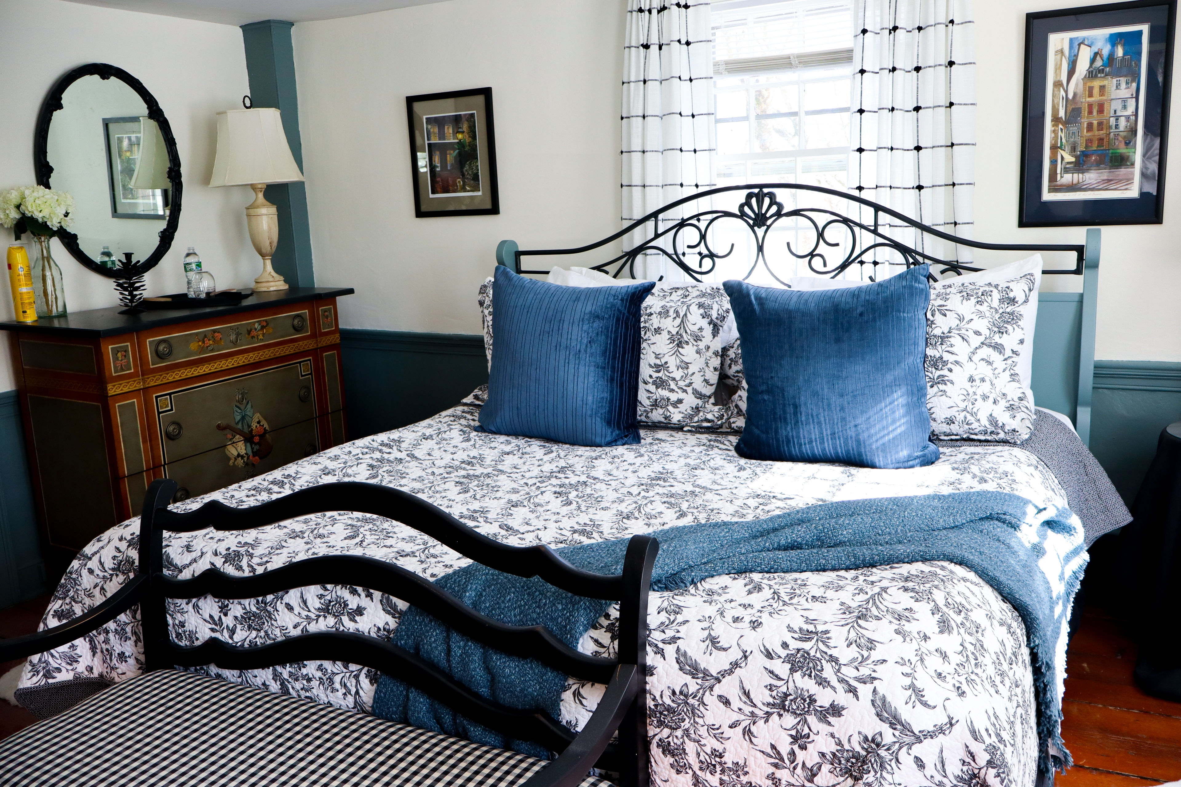 A cozy corner featuring a lit fireplace with a bright green mantel, a plaid armchair, and floral wallpaper, creating a quaint, warm atmosphere.