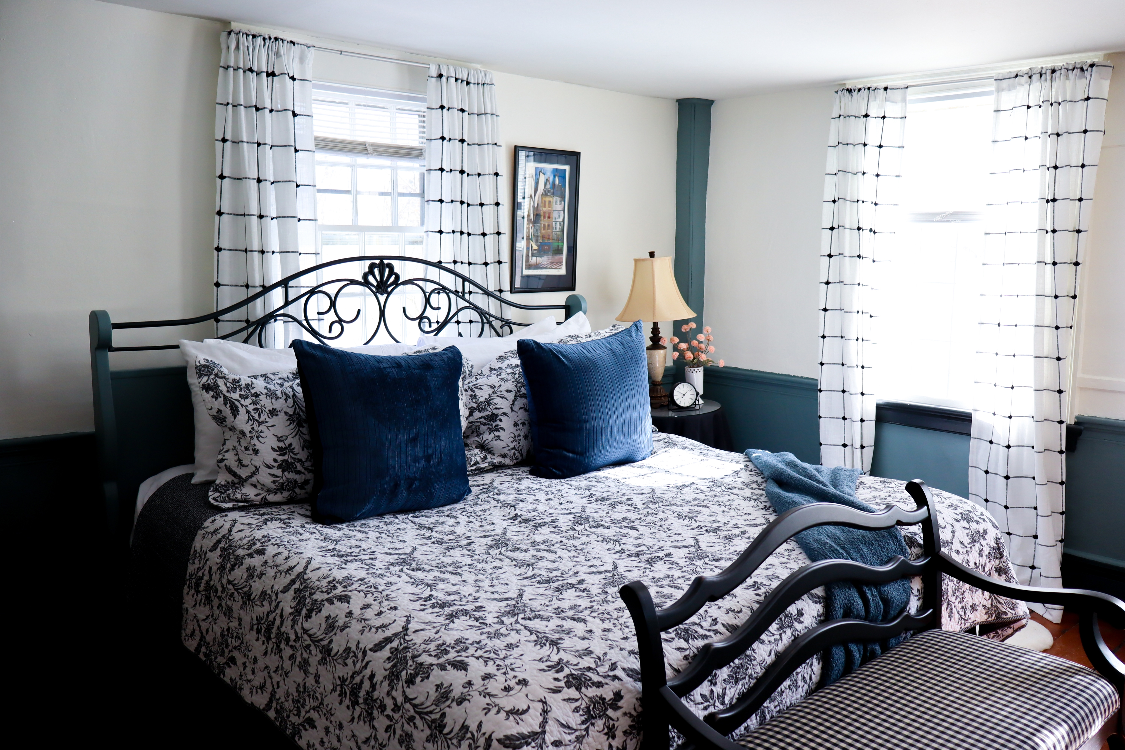 A quaint room featuring delicate floral wallpaper, bright green trim, a small wood writing desk with a lamp, and an open doorway.