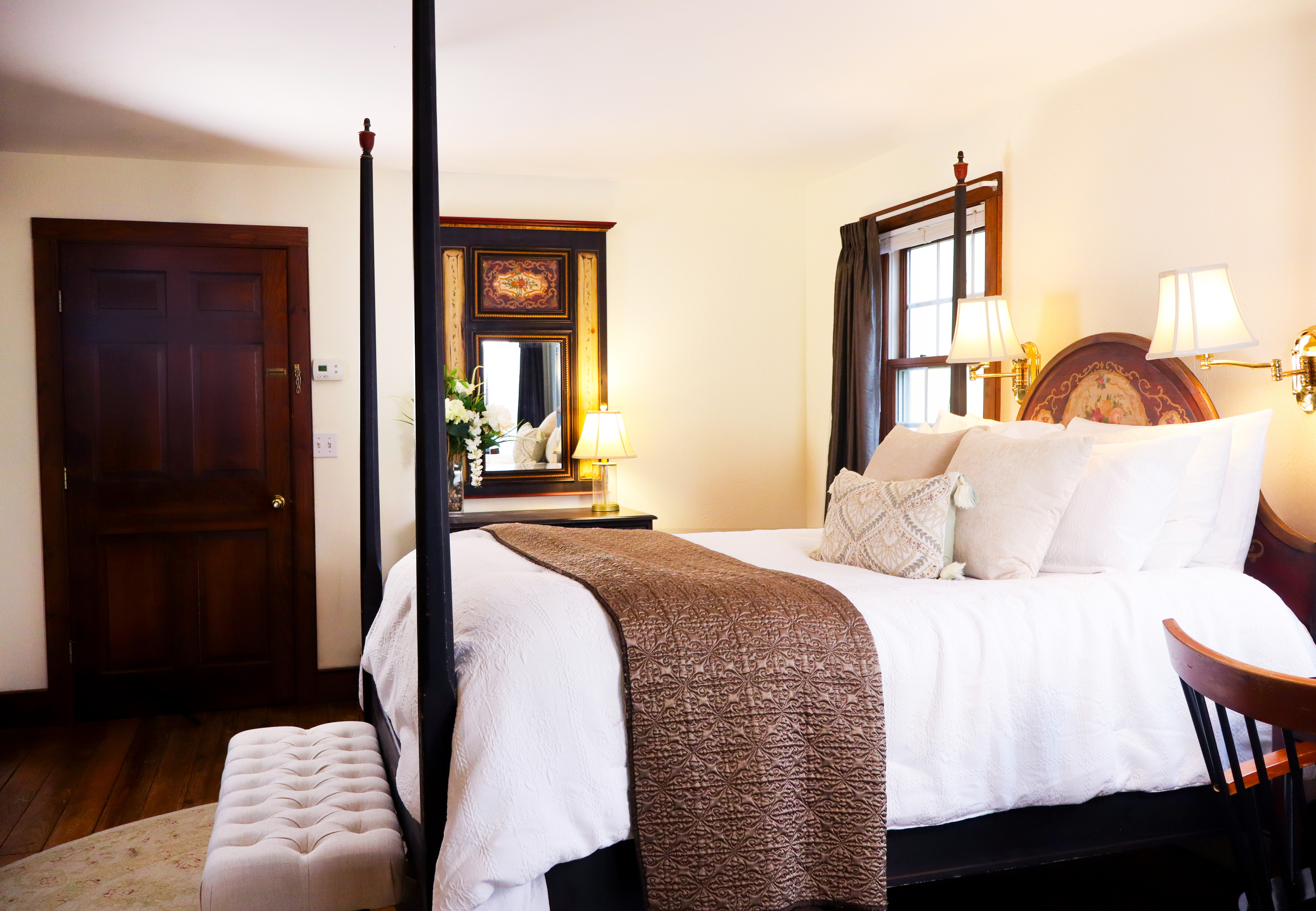 A charming sitting area featuring a lit fireplace, a built-in cabinet mantelpiece, two cozy armchairs, and a tray with wine glasses.