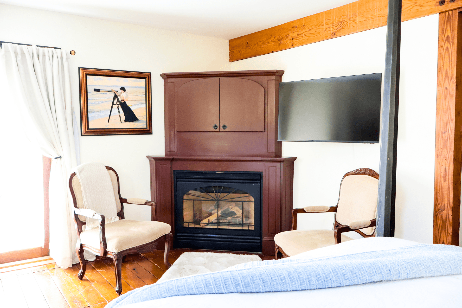 A relaxing bathroom with a deep jetted tub encased in dark wood, a small rose, wine glasses, and a vanity with a framed mirror.