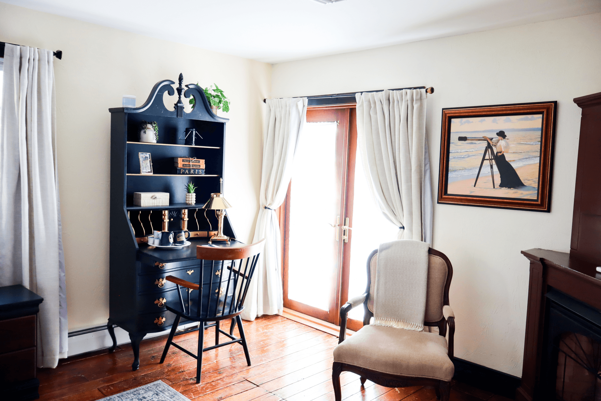 A well-lit bathroom featuring a glass-enclosed walk-in shower with a robe hanging nearby, and a vanity area with a mirror and stool.