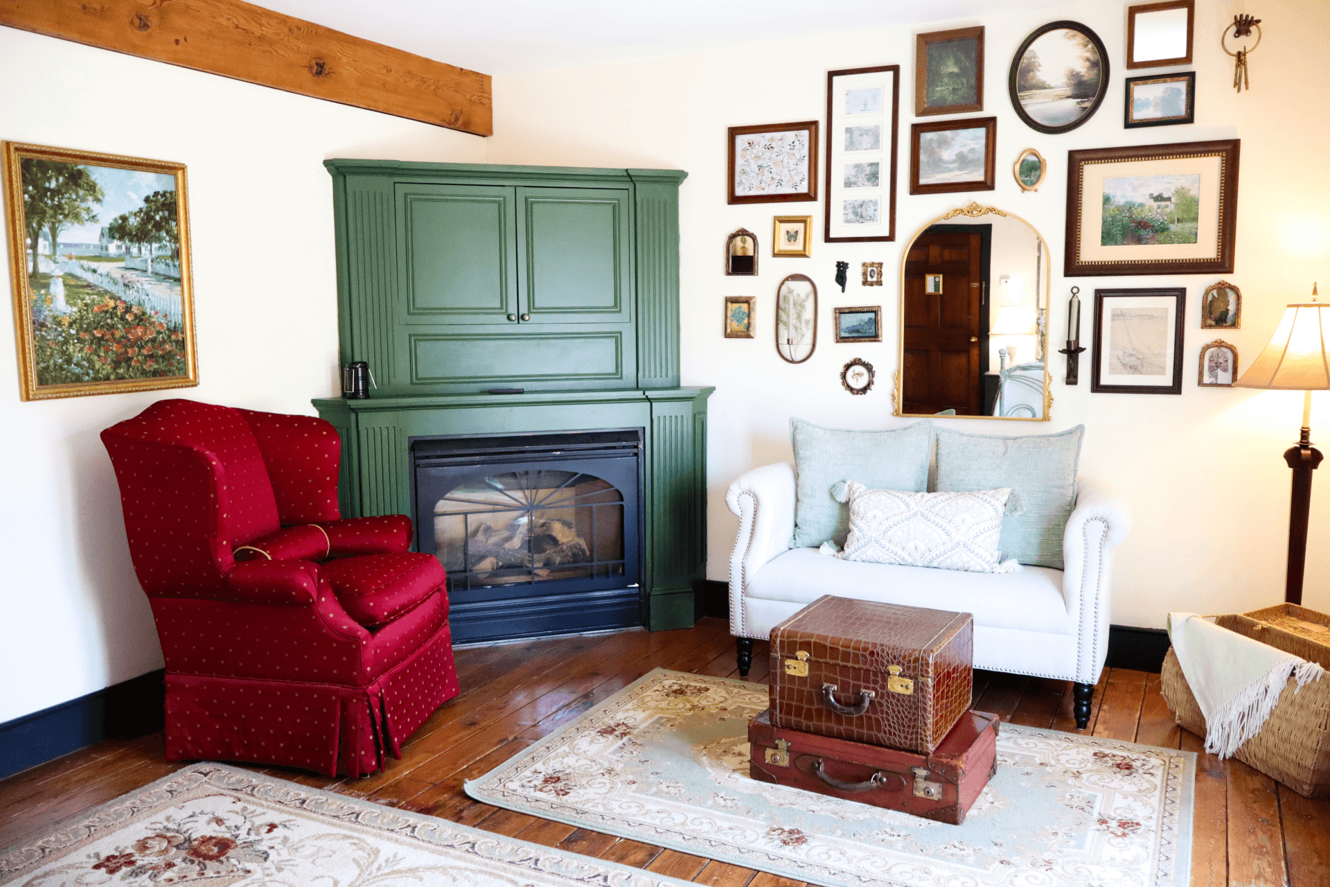 A cozy sitting area featuring a lit fireplace set in a sage-green mantel, a comfortable sofa with pillows, and a small table with flowers.