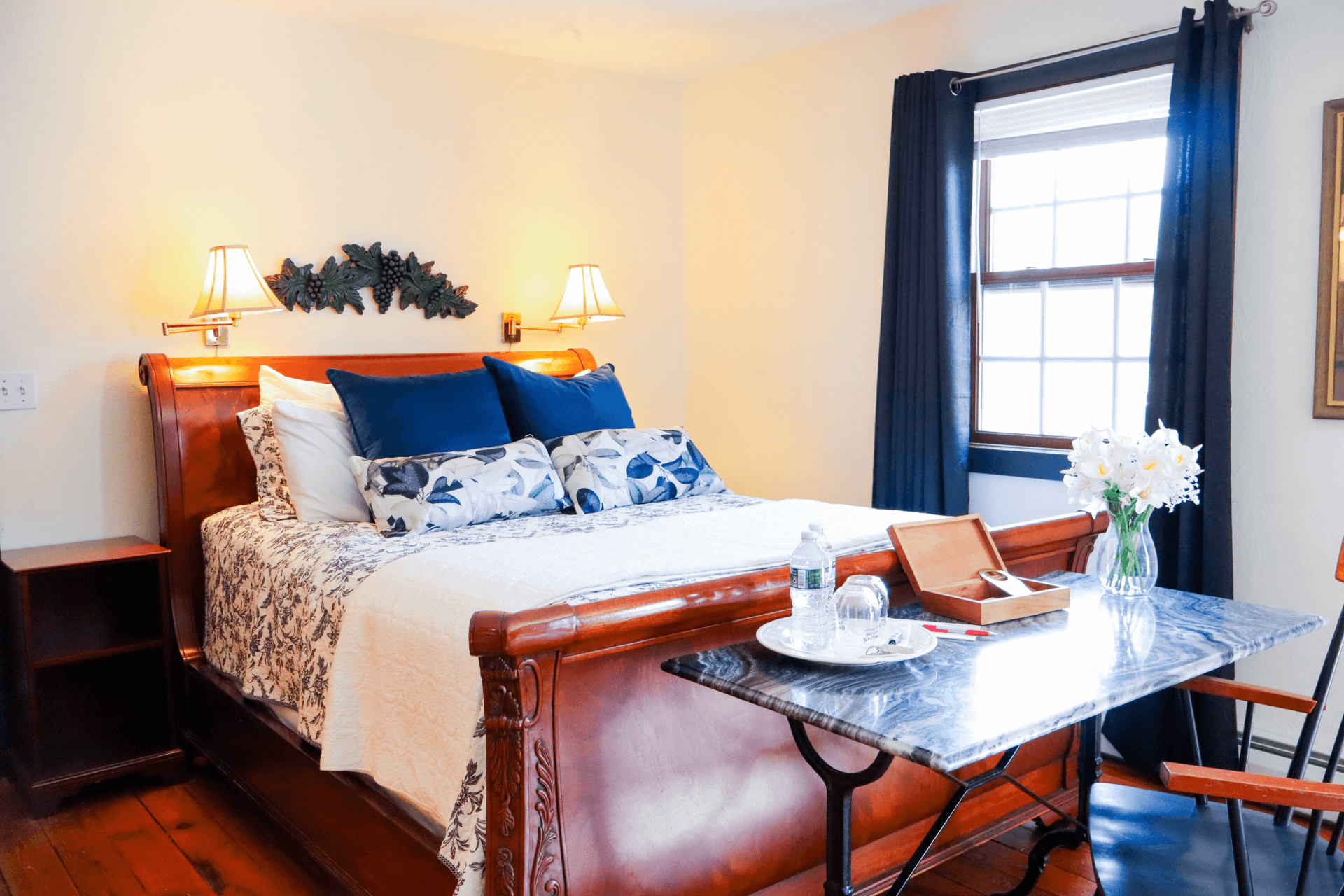 A richly decorated bedroom featuring a warm wooden sleigh bed with burnt orange and brown bedding, illuminated by two bedside lamps.