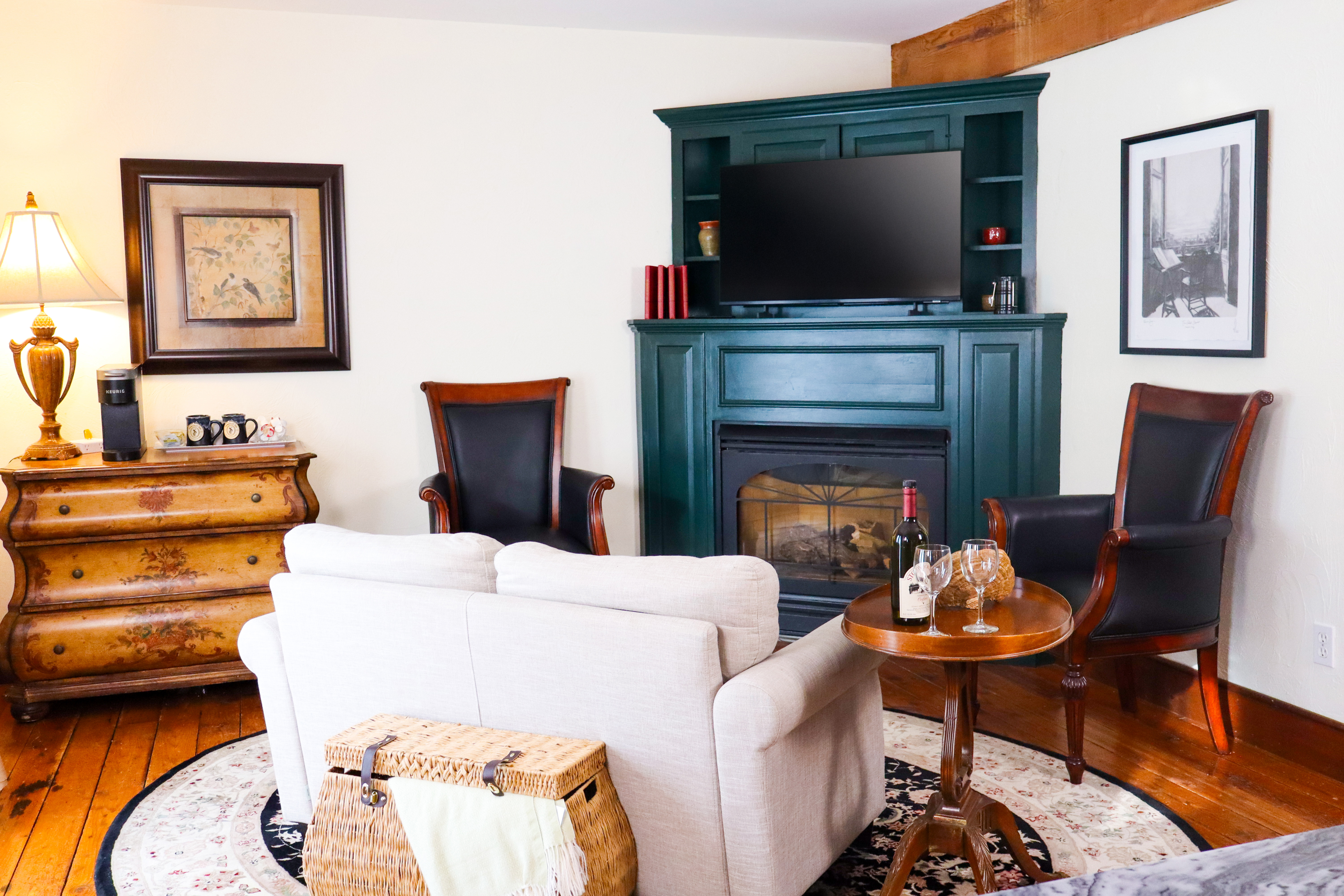 A charming outdoor deck with yellow siding, a small bistro table for two with wine glasses, and a view of surrounding greenery.