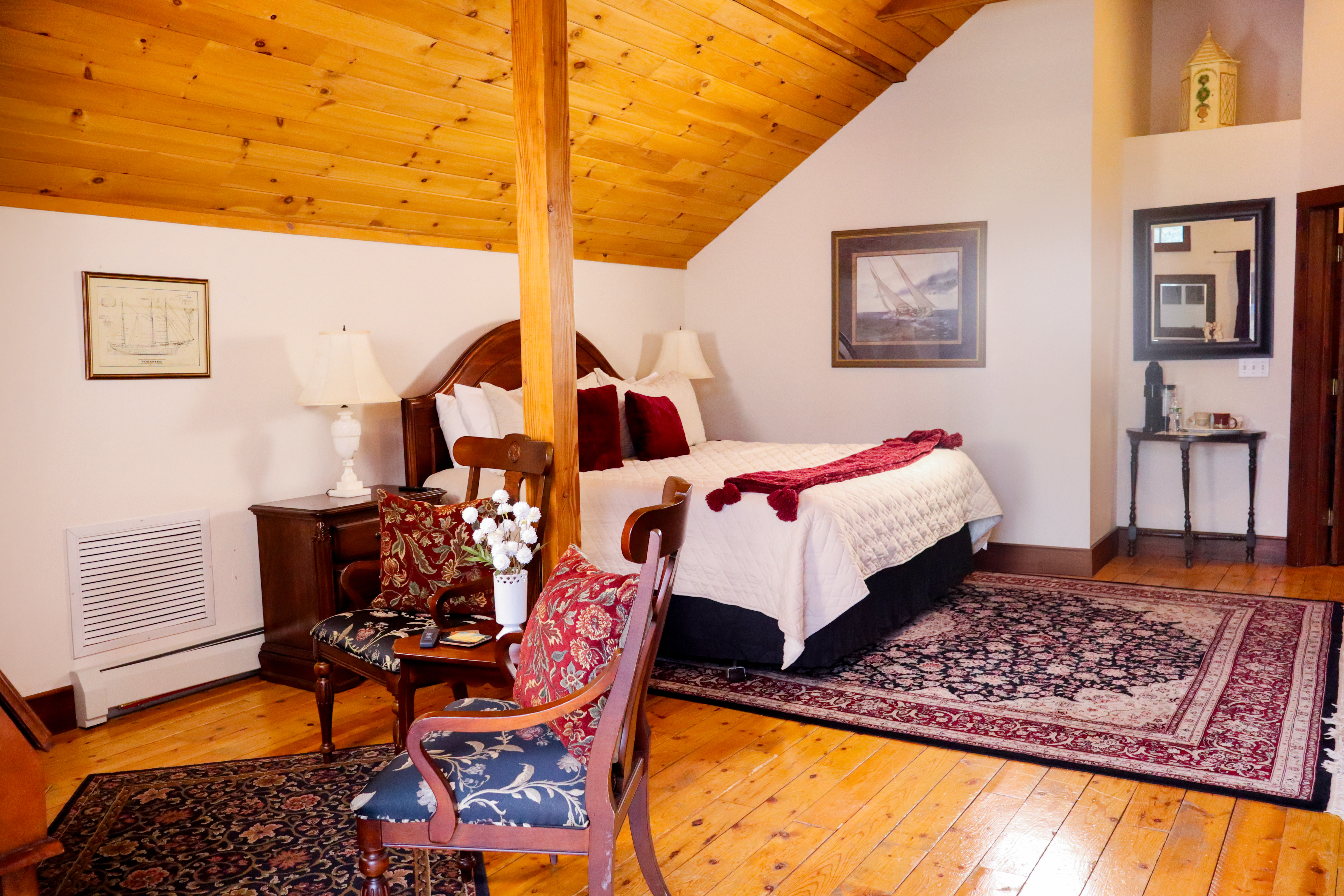 A bright, spacious bathroom with a wood-planked ceiling, a dark wood vanity, and an ornate gold-framed mirror.