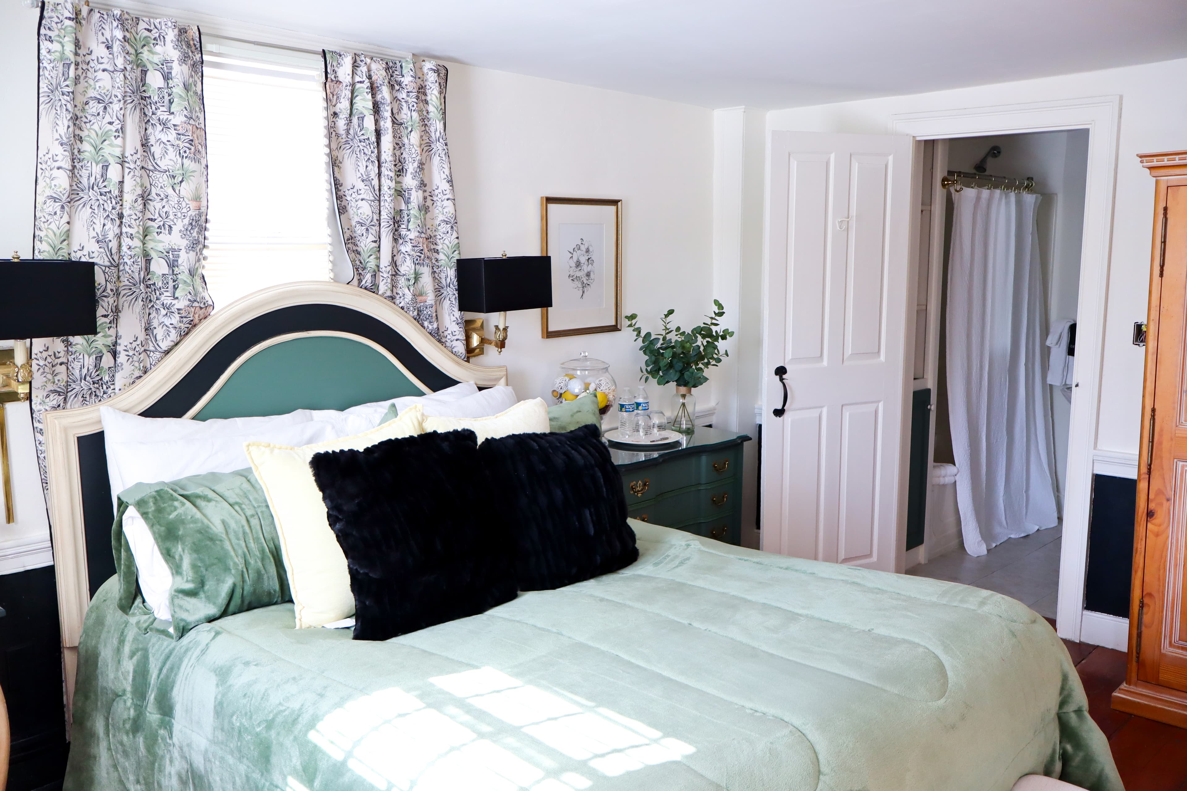 A small, charming bathroom featuring a pedestal sink with gold fixtures, a tub/shower combo, and built-in shelving with flowers.