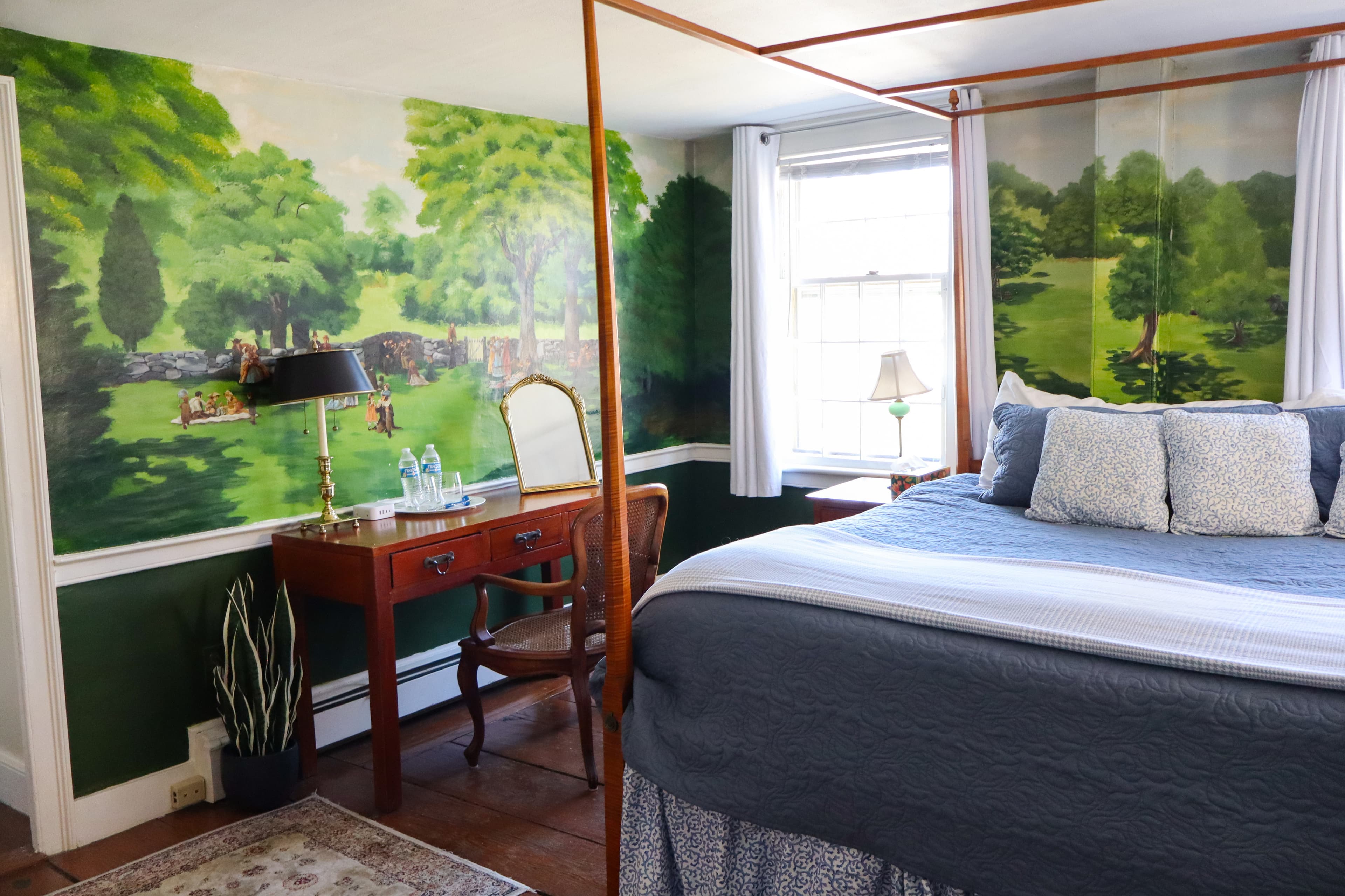 A close-up of a cozy bed with layered white and brown pillows, a white bolster, and a soft pink/peach blanket.
