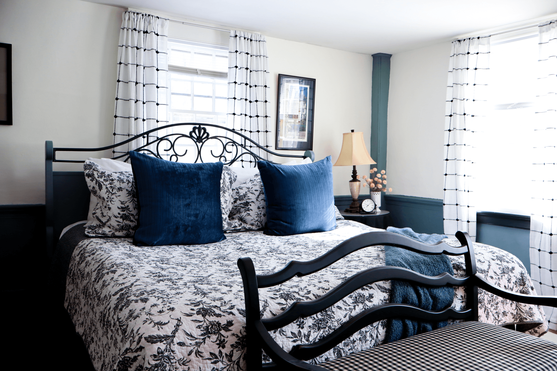 A cozy corner featuring a lit fireplace with a bright green mantel, a plaid armchair, and floral wallpaper, creating a quaint, warm atmosphere.