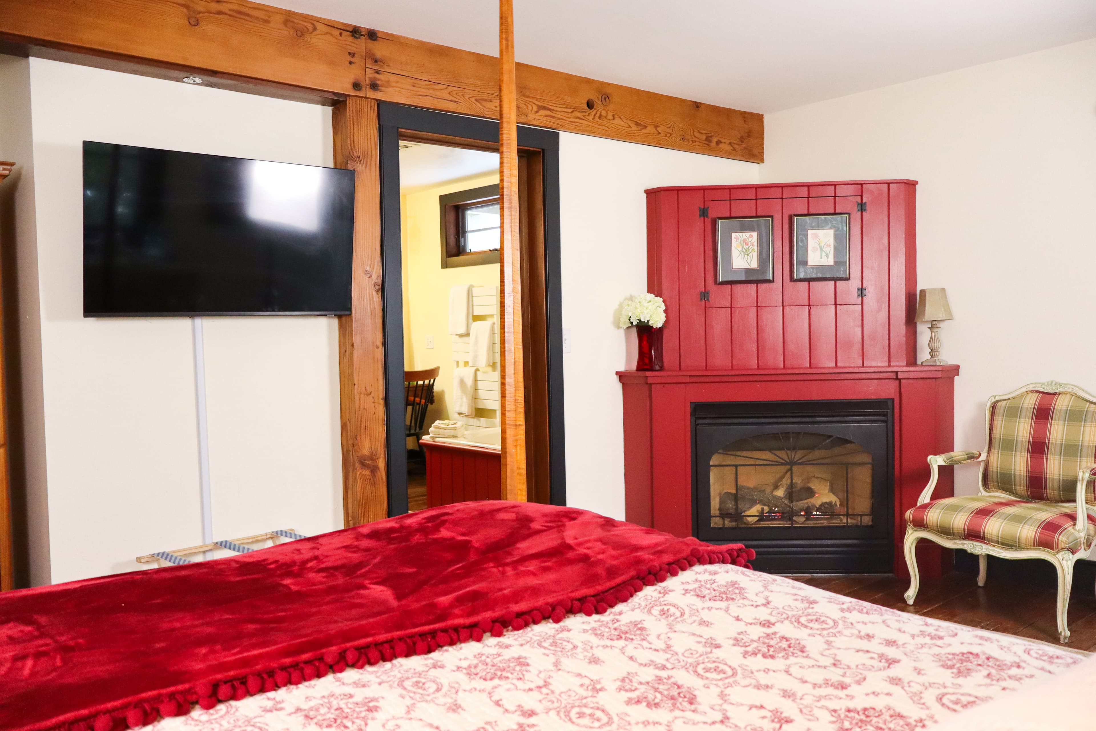 A luxurious four-poster bed with sheer white drapes is the centerpiece of this romantic, well-appointed bedroom with warm wood accents.