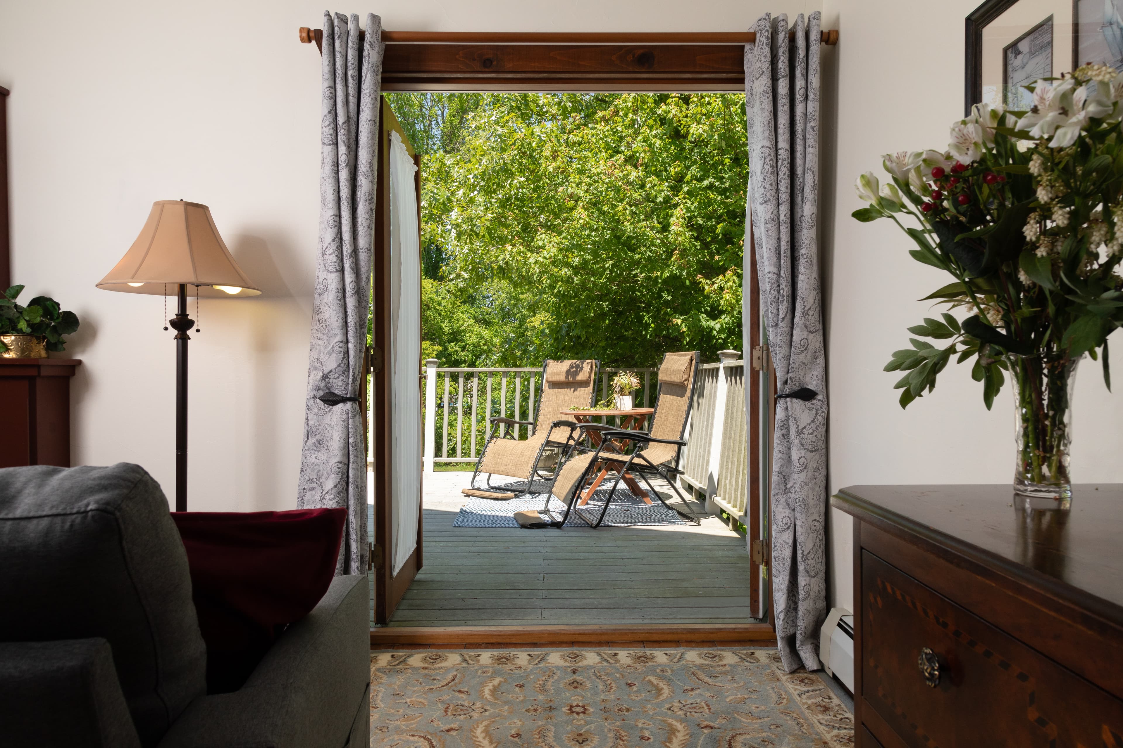 French doors open from an indoor seating area onto a private deck with lounge chairs.