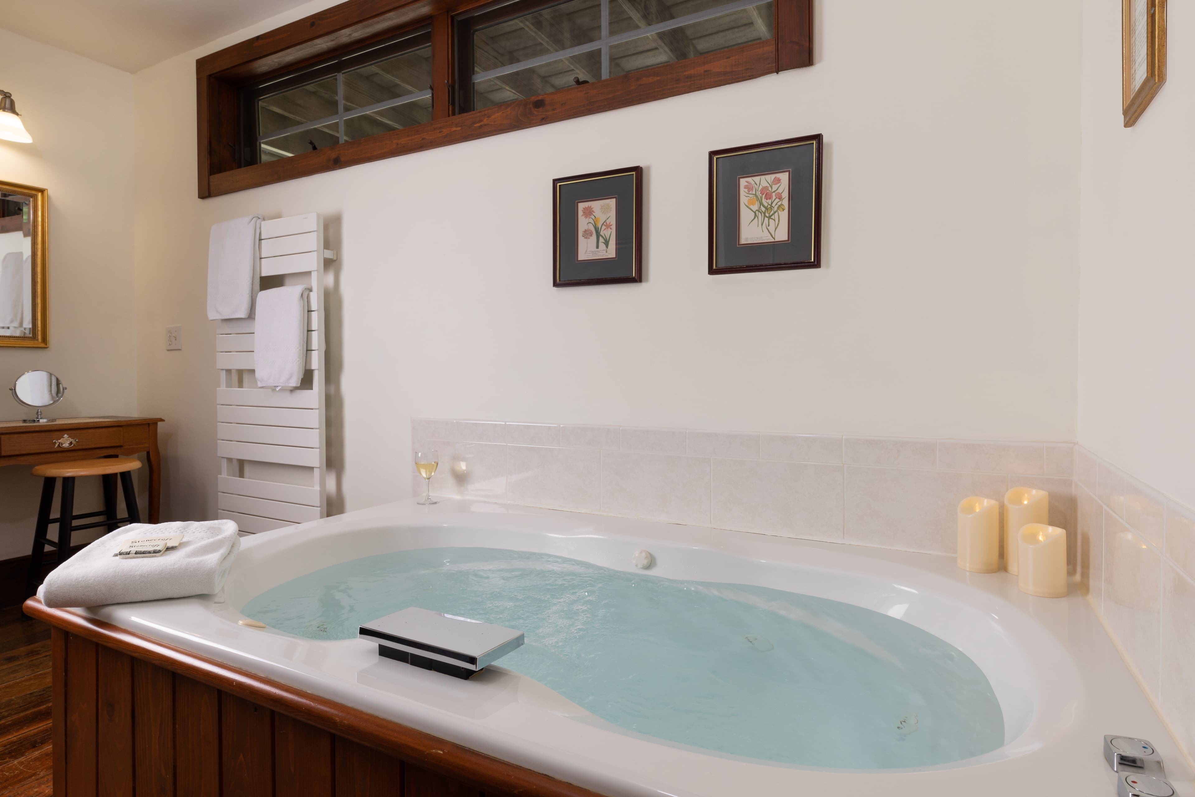A bright, luxurious bathroom featuring a large jetted tub with a bath caddy and candles.