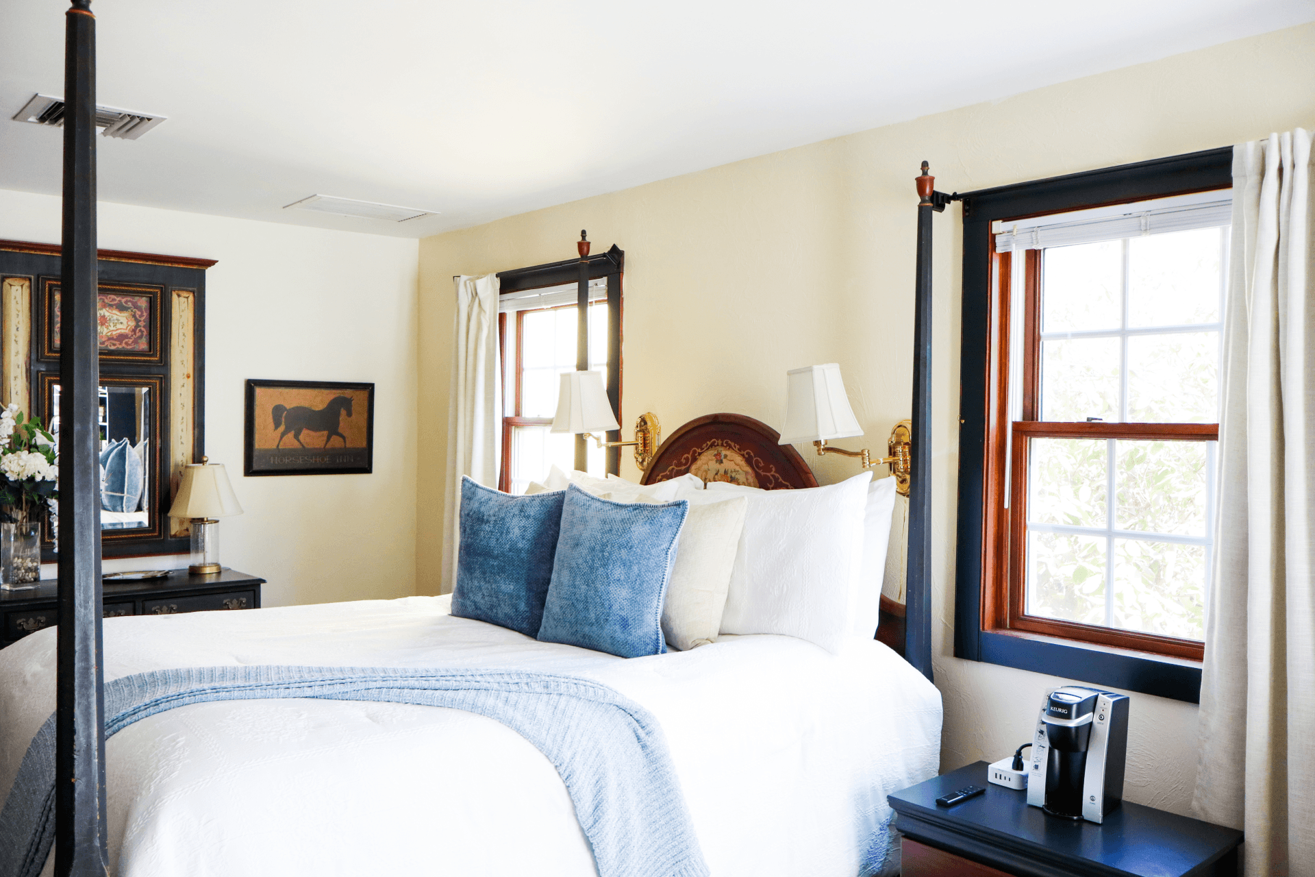 A charming sitting area featuring a lit fireplace, a built-in cabinet mantelpiece, two cozy armchairs, and a tray with wine glasses.