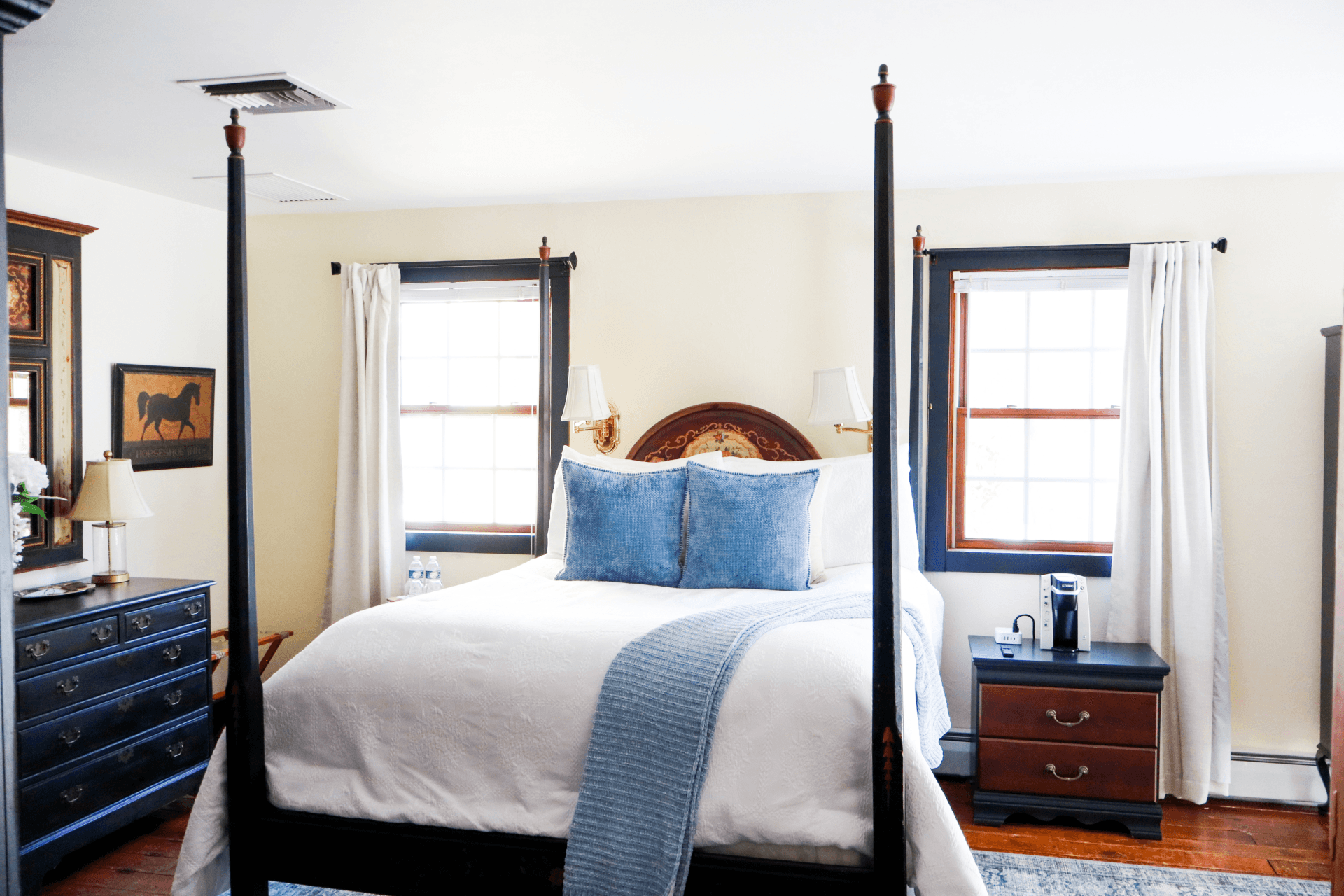 An inviting bedroom featuring a queen bed, a cozy corner fireplace, and French doors leading outside.