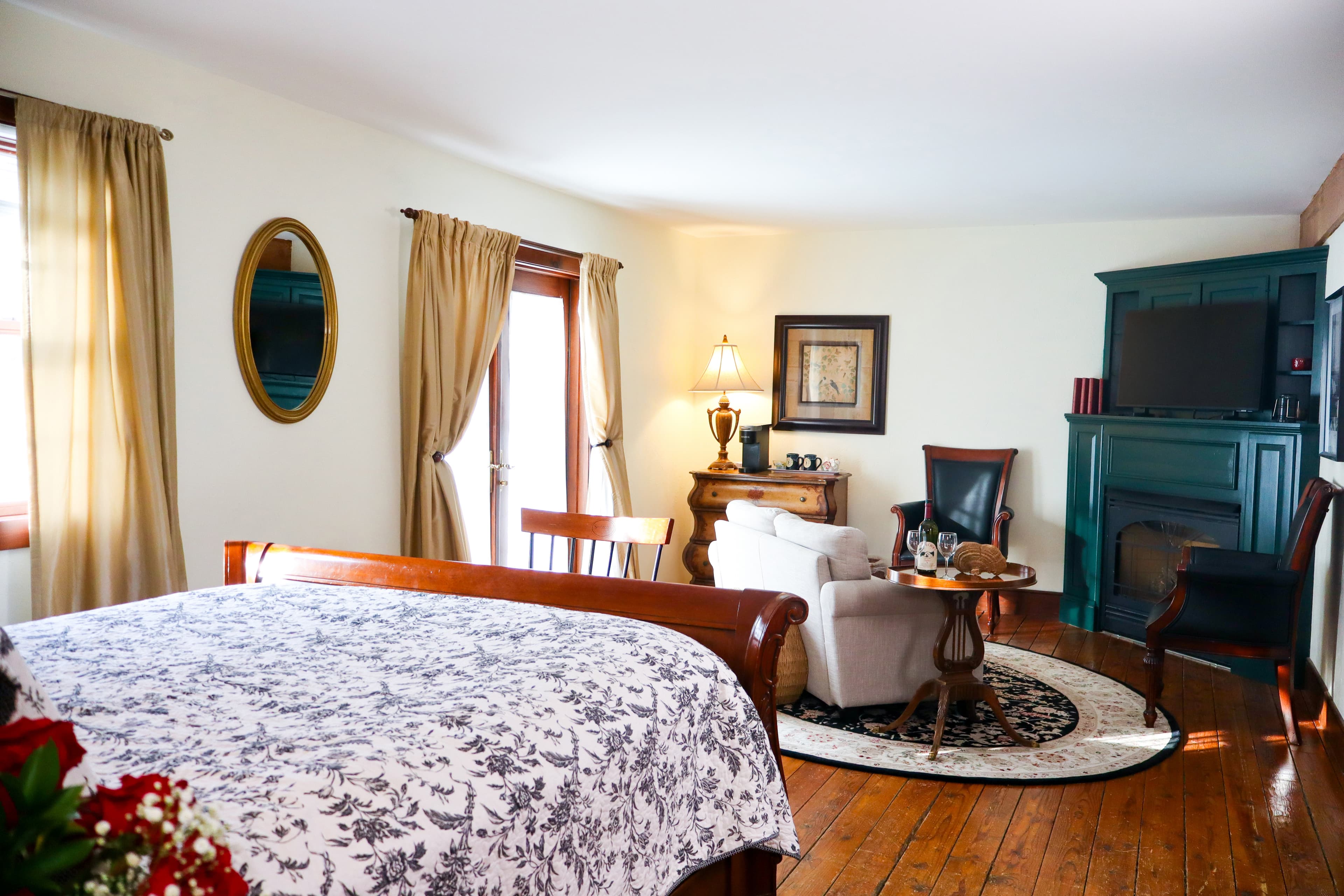 A romantic setting with a large jetted tub, two glasses of red wine, fresh flowers, and soft towels.