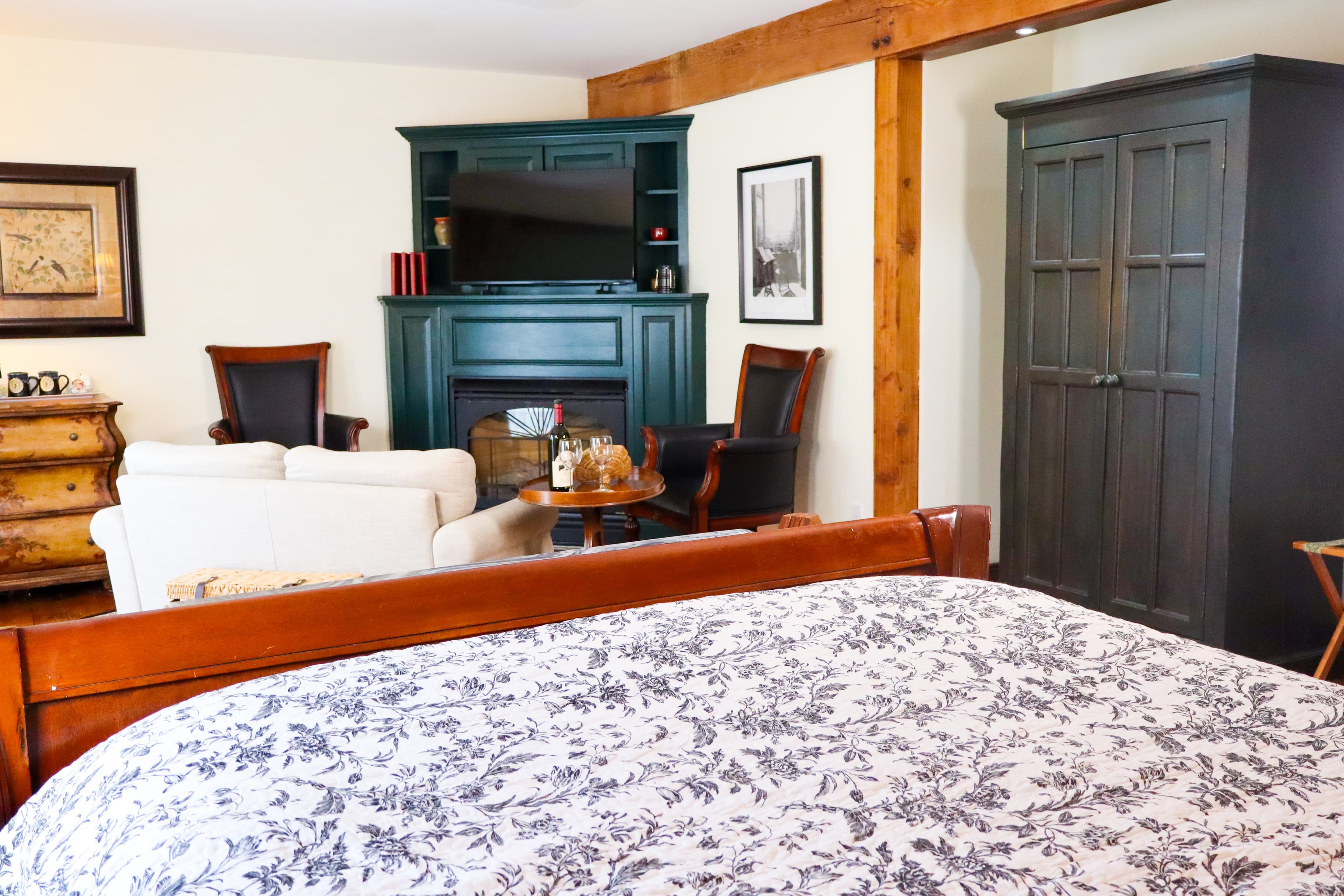 Cozy bedroom featuring a bed with floral bedding, a fireplace, and comfortable seating.