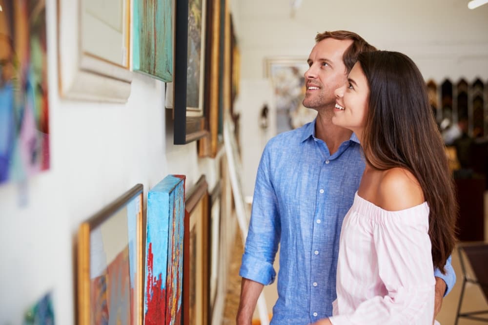 A couple admires artwork in a gallery.