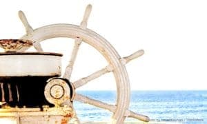 A ship's wheel with ocean in the background.
