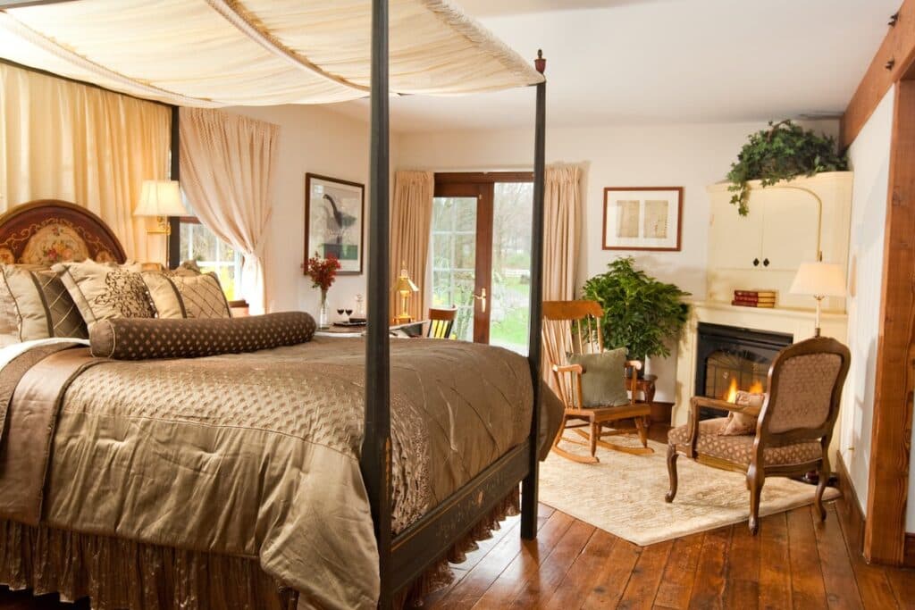 A cozy bedroom featuring a four-poster bed, soft lighting, and a fireplace.