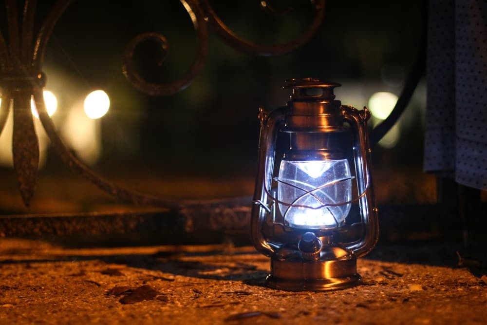 A vintage lantern emits light against a blurred nighttime background.