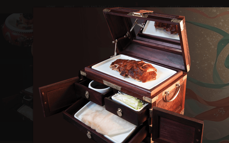 A wooden box displaying sliced roasted duck along with garnishes and sauces inside.