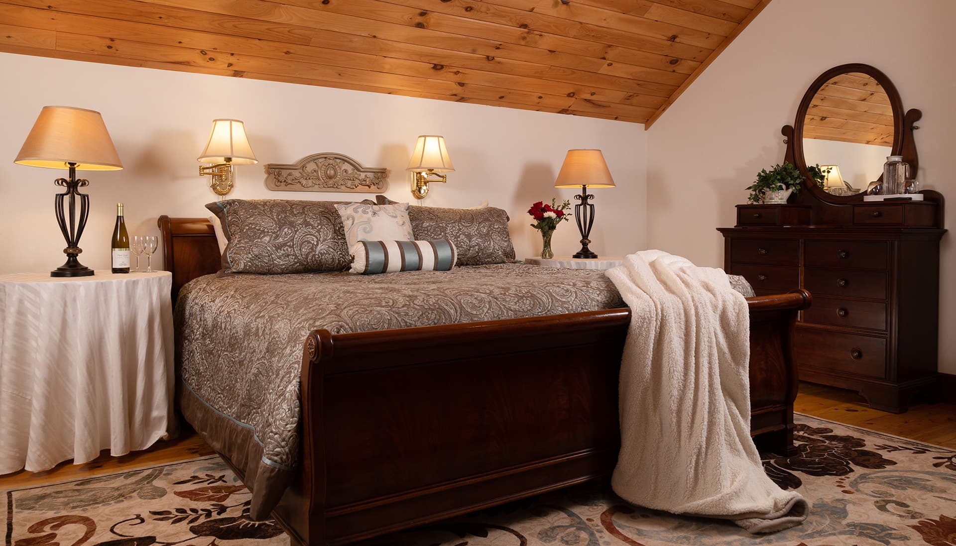 Cozy bedroom featuring a wooden bed, decorative pillows, lamps, and a dresser.