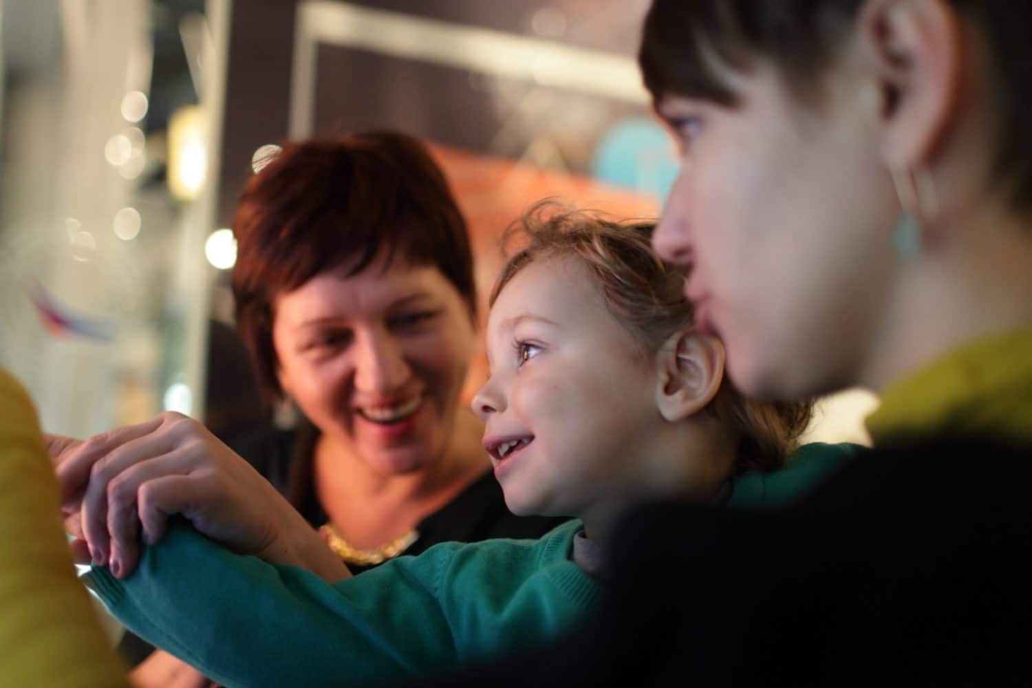 A child joyfully engages with two adults in a warm, interactive moment.