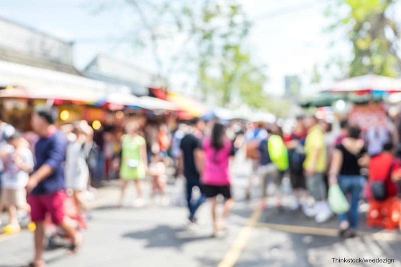 A bustling market scene with blurred crowds and colorful stalls.