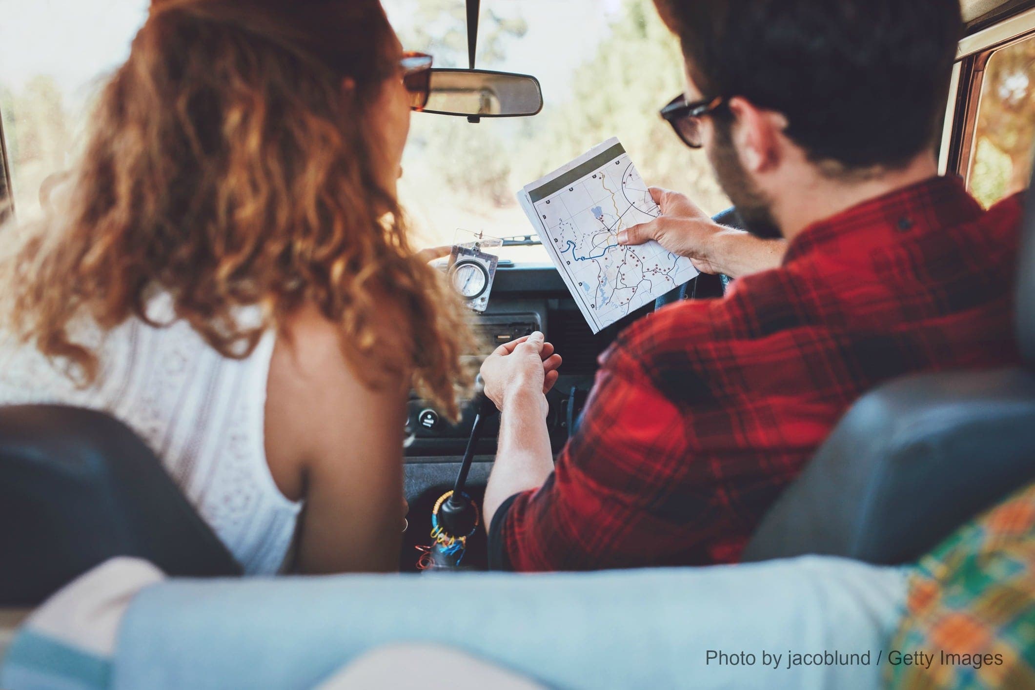 A couple evaluates a map inside a vintage vehicle.