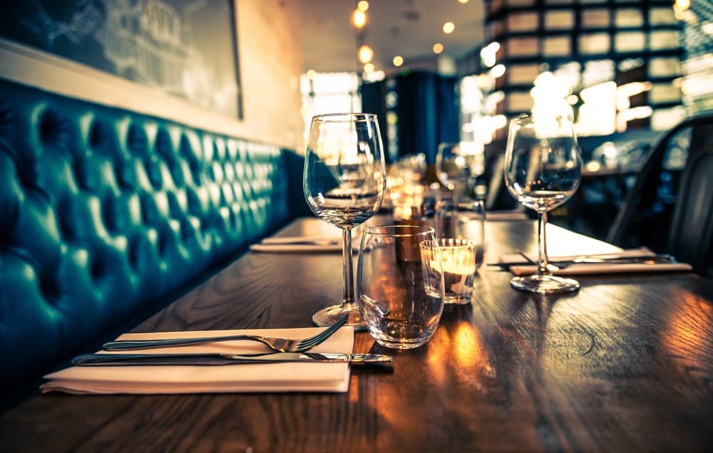 A beautifully set dining table with glassware and candles in a cozy restaurant.