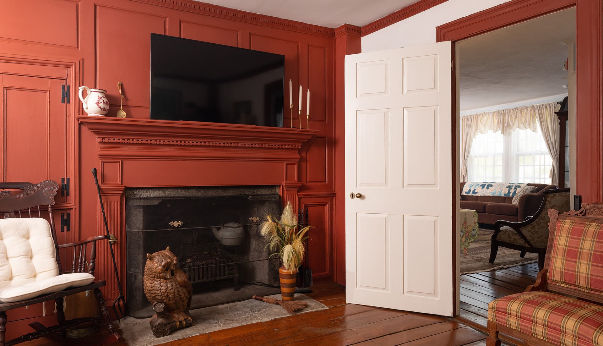 Cozy living room with a red paneled wall, fireplace, and an open door leading to another room.