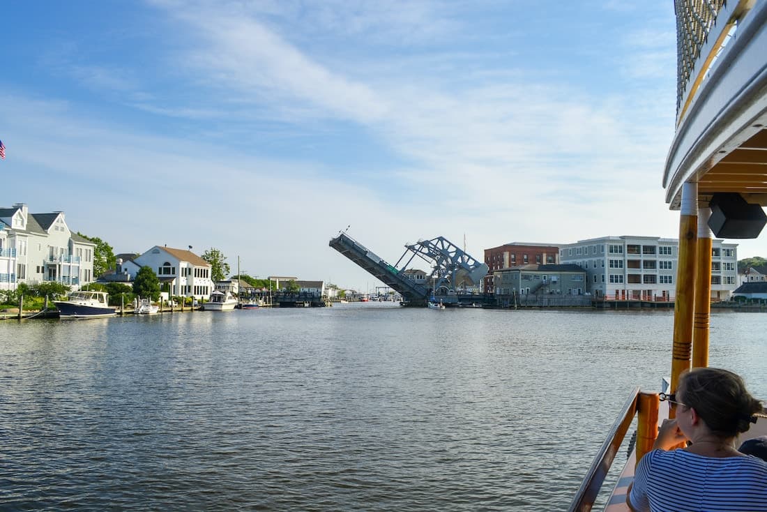 A river scene featuring a raised drawbridge with boats and waterfront buildings nearby.