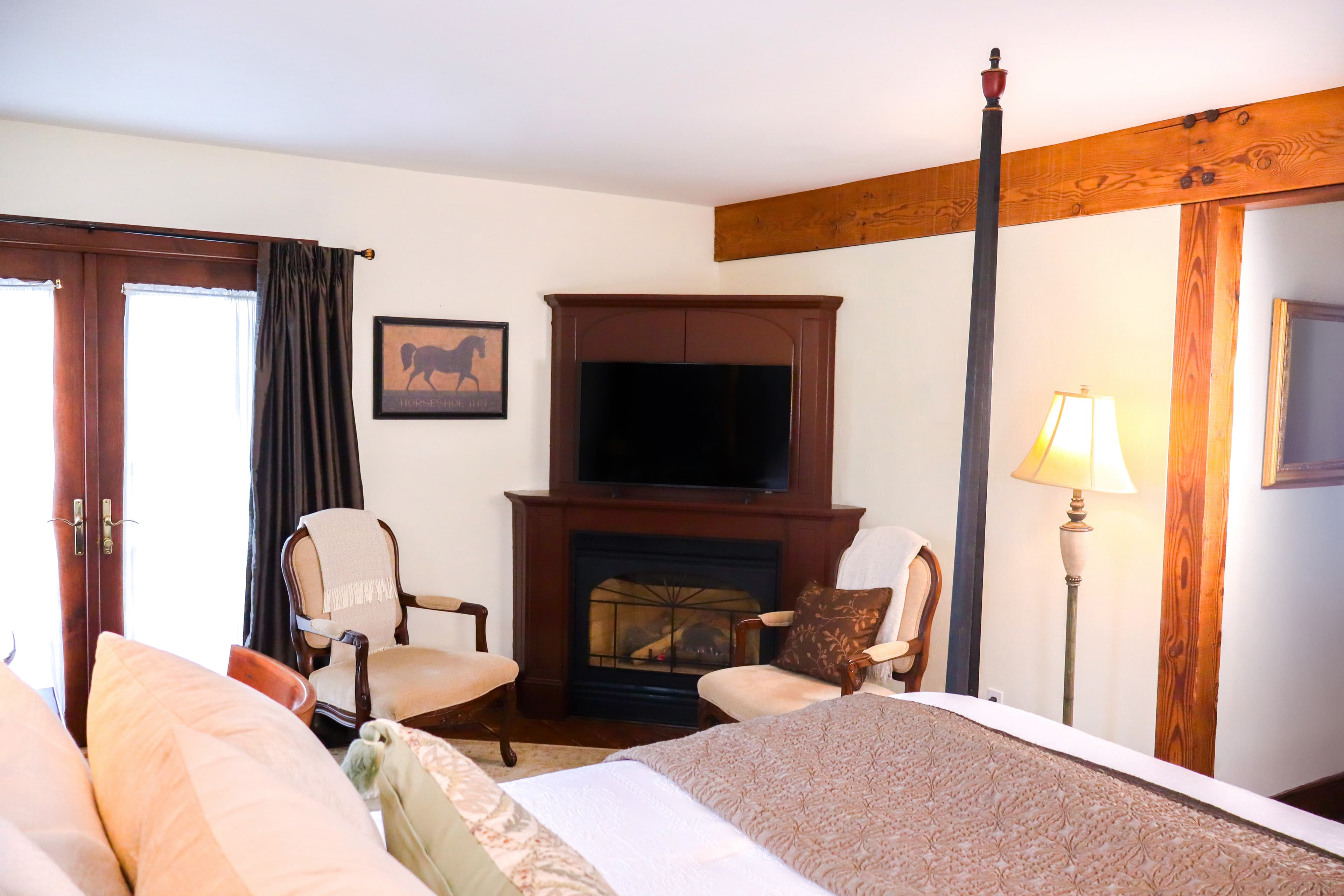 Cozy bedroom with a fireplace, TV, and seating area near large windows.