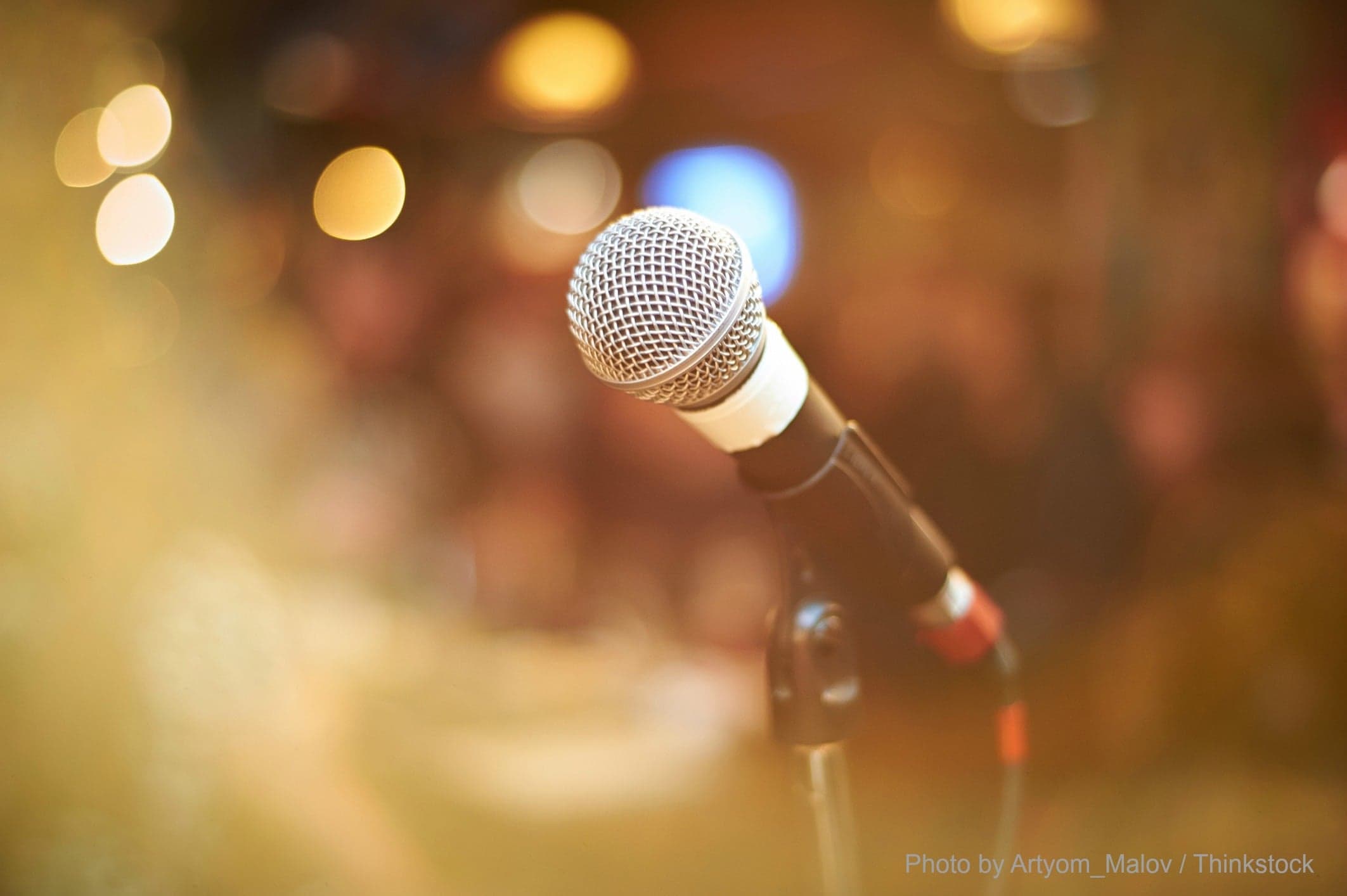A close-up of a microphone on a stand with a blurred background.