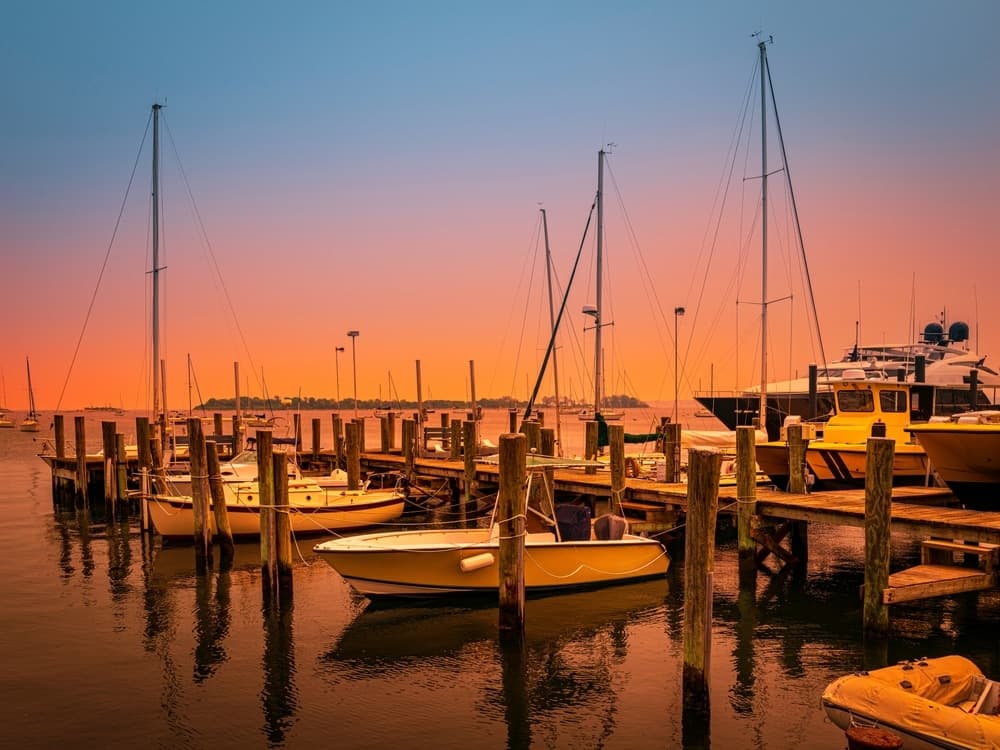 Boats are moored at a dock during a vibrant sunset.