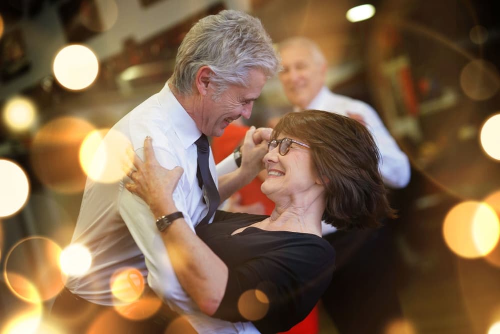 A joyful couple dances closely together, surrounded by a warm, festive atmosphere.