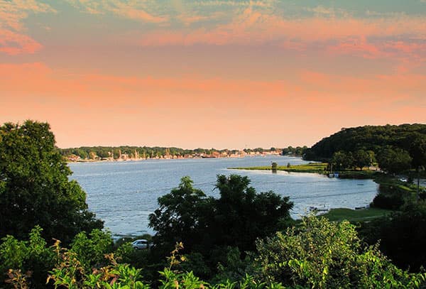 A serene lakeside view at sunset with lush greenery in the foreground.