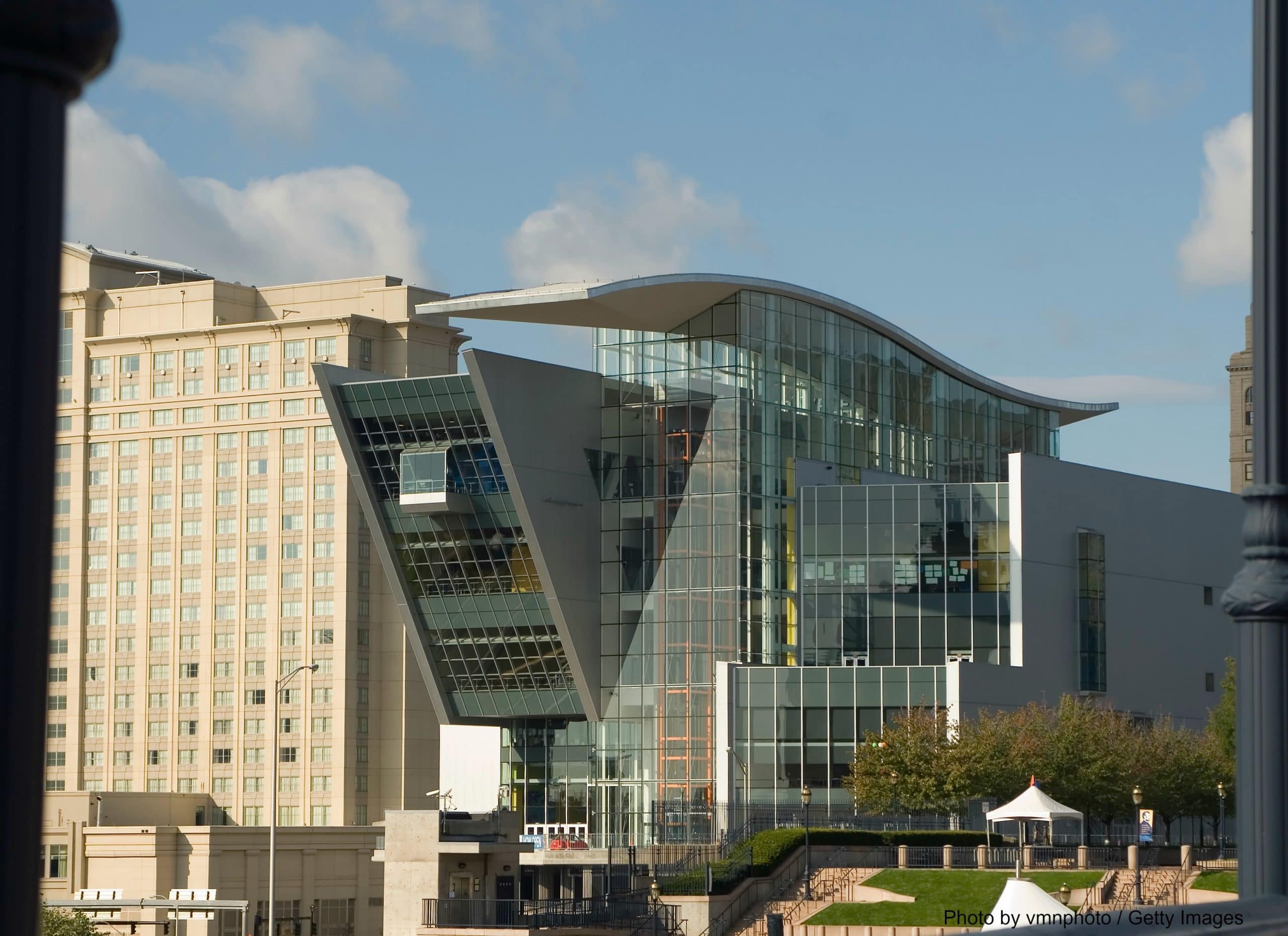 Modern glass building with a distinctive angular design, surrounded by other urban structures.