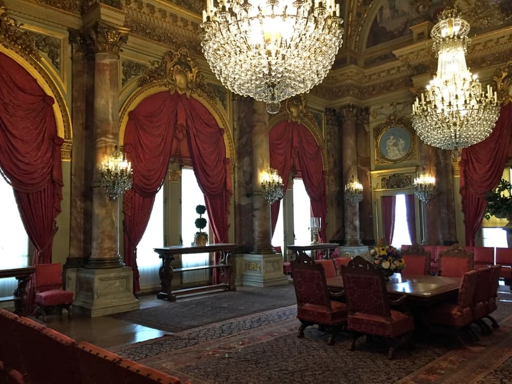 A lavishly decorated room featuring ornate chandeliers, rich red drapes, and elegant furniture.