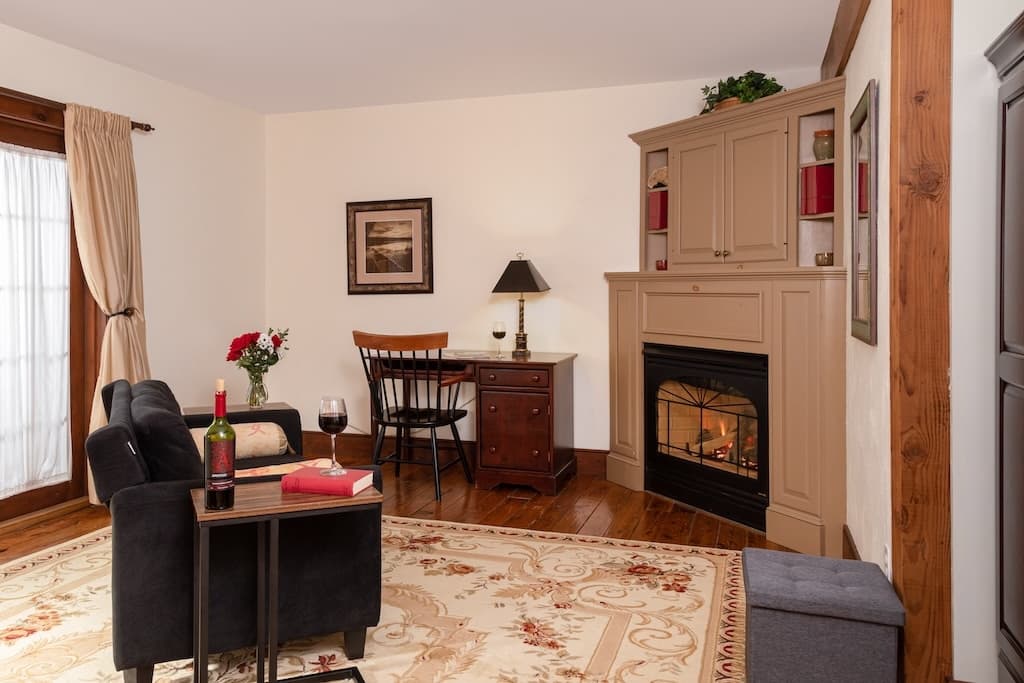 Cozy living room with a fireplace, dark furniture, and a small dining area.