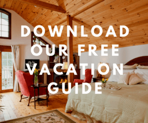 Cozy bedroom with a wooden ceiling and two red armchairs, featuring text promoting a free vacation guide.