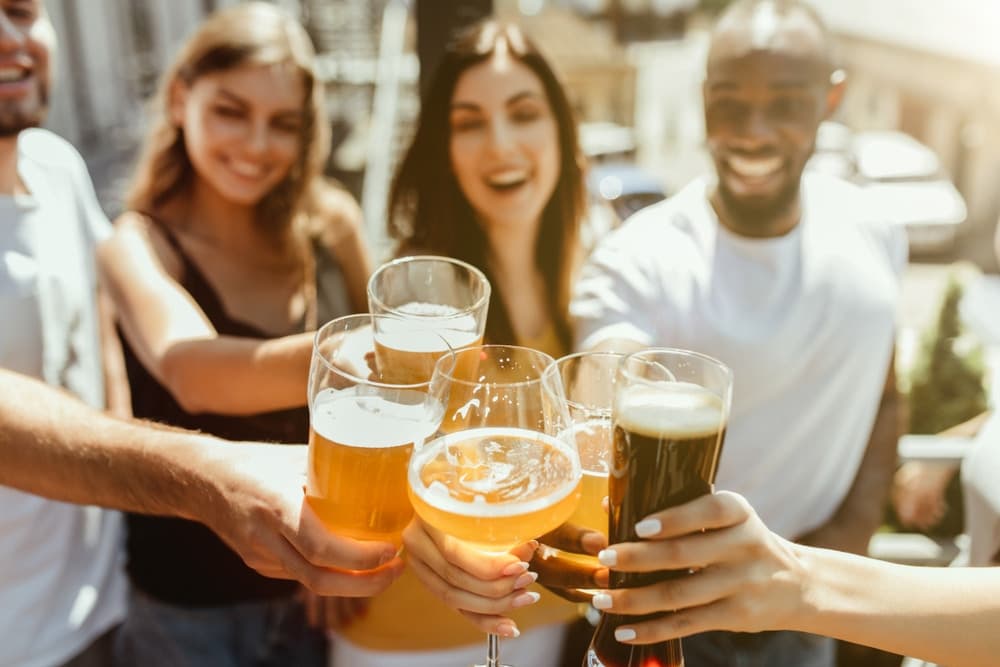 A group of five friends cheerfully clink their glasses filled with various types of beer.