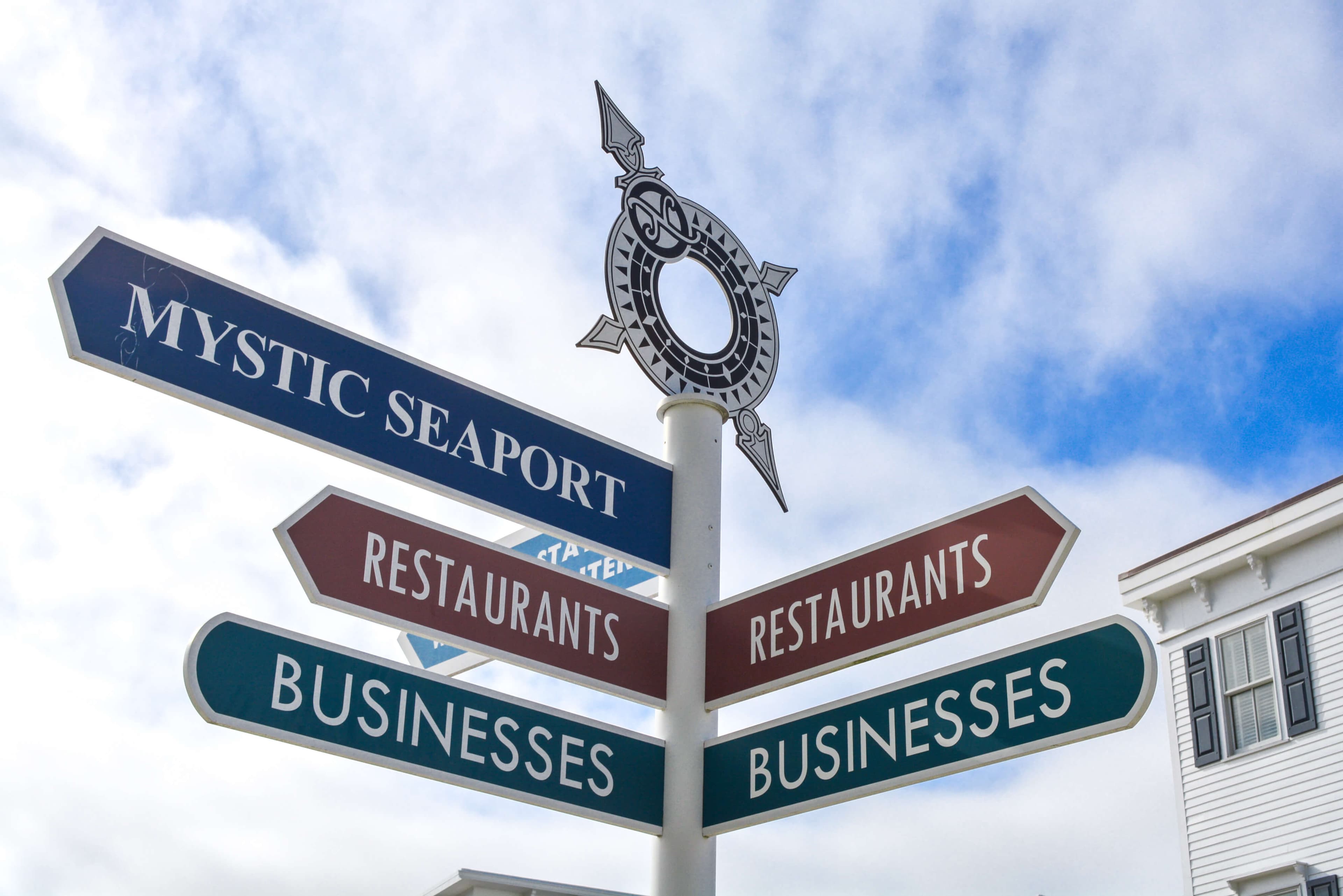 A directional signpost with arrows pointing to "Mystic Seaport," "Restaurants," and "Businesses." A directional signpost with arrows pointing to "Mystic Seaport," "Restaurants," and "Businesses."