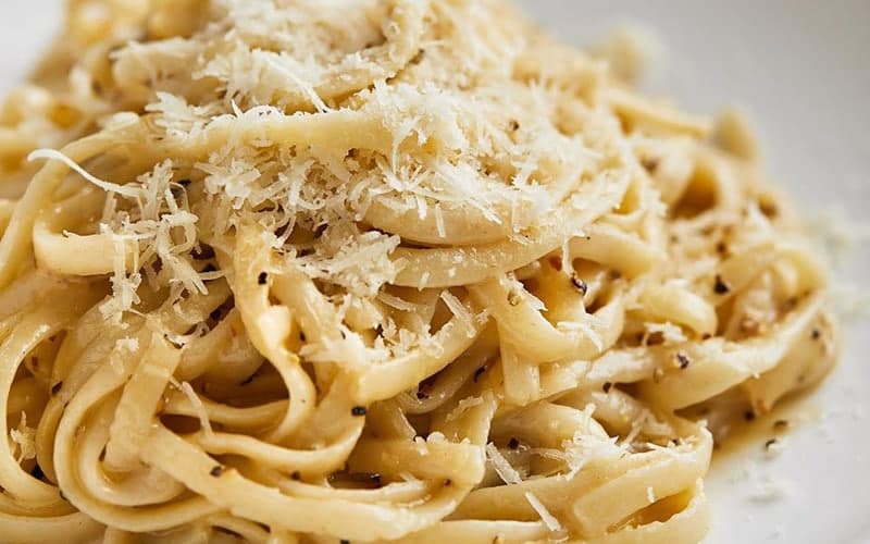 Plate of creamy fettuccine pasta topped with grated cheese.