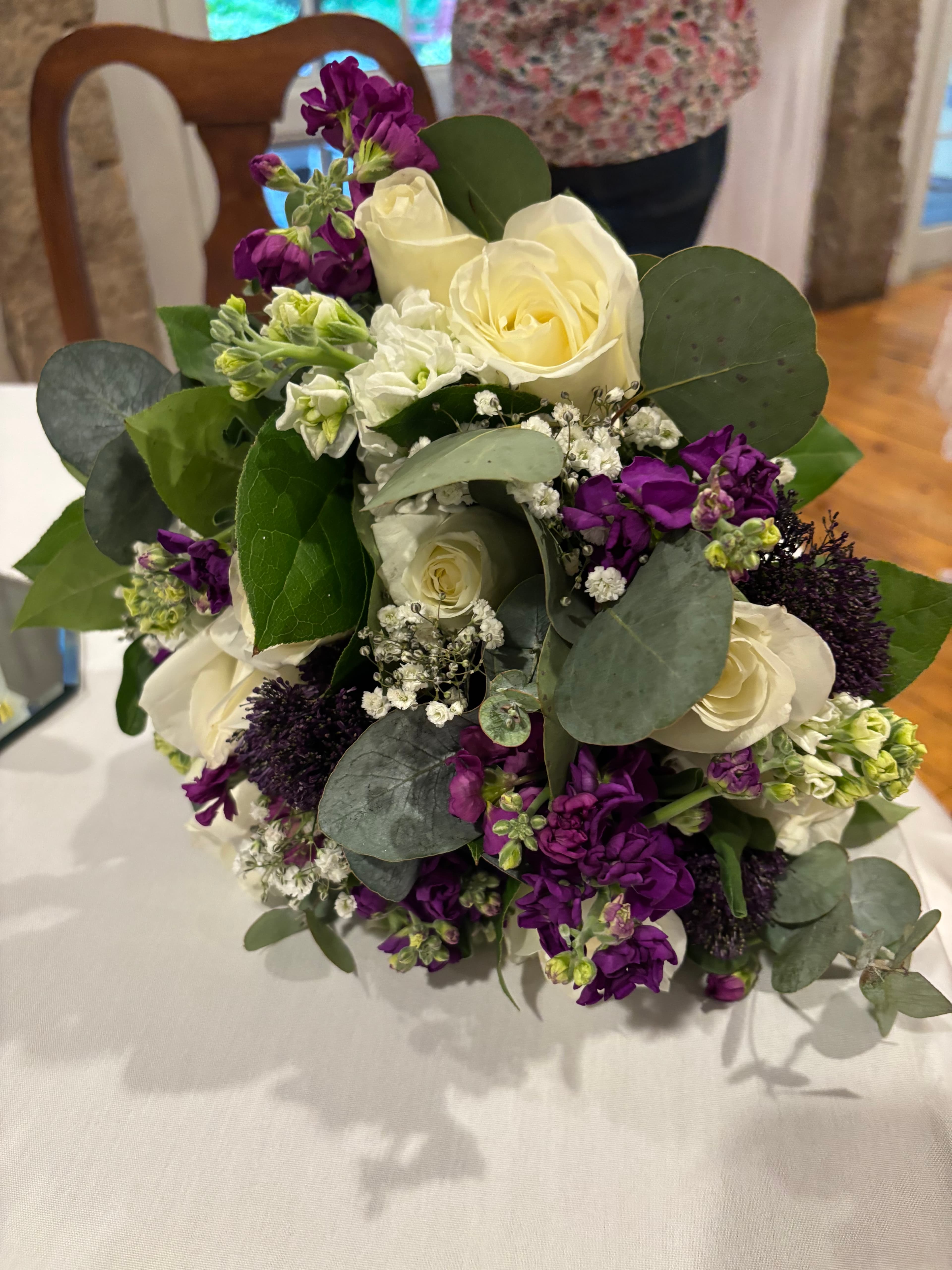 A bouquet of white and purple flowers surrounded by greenery.