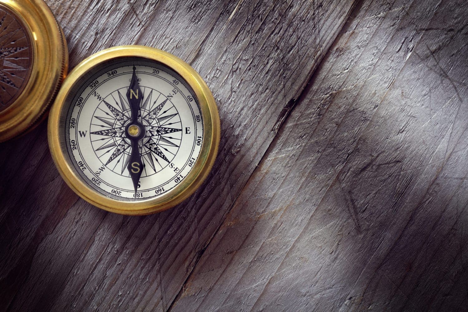 A vintage compass resting on a wooden surface.