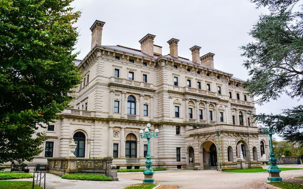 A grand, historic mansion with intricate architecture surrounded by greenery.