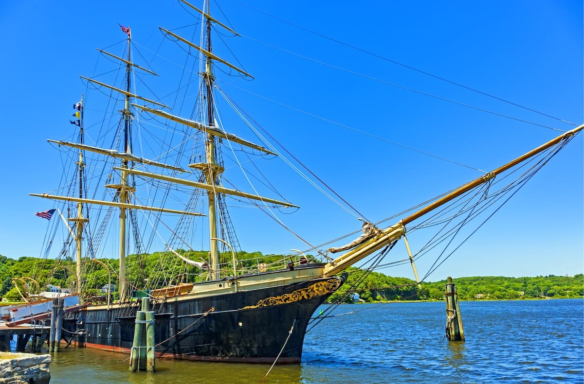 A historic tall ship docked in the water on a clear day.