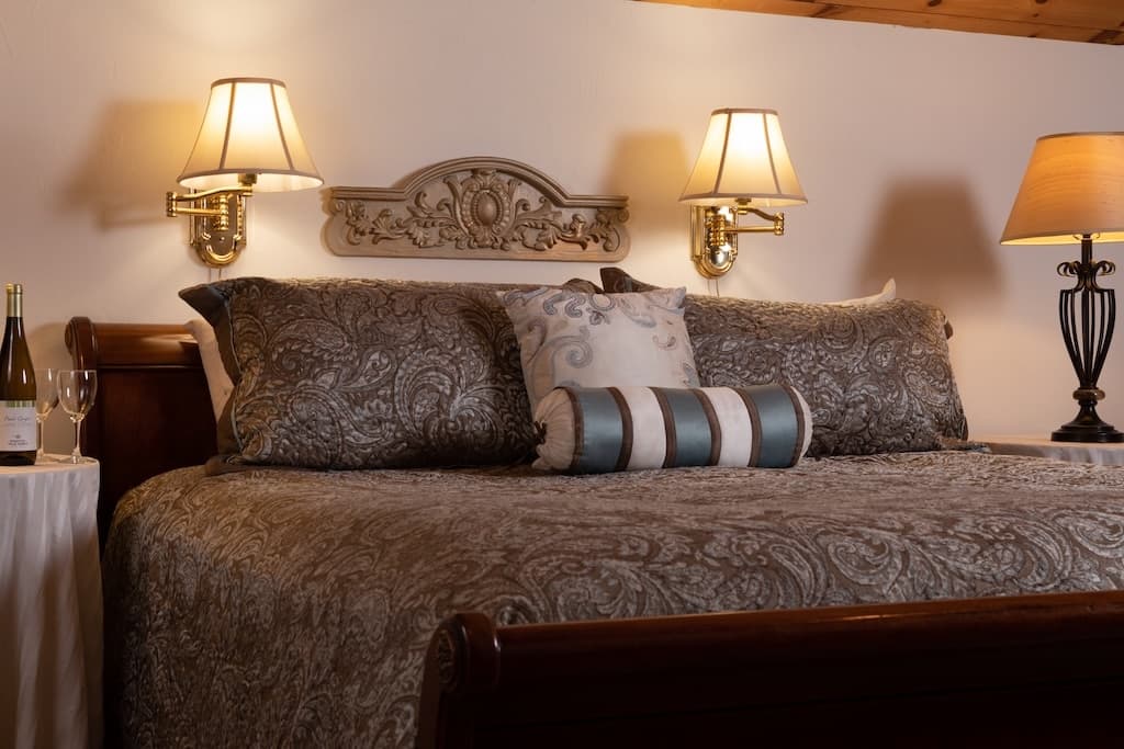 Elegant bed with decorative pillows, surrounded by soft lighting.