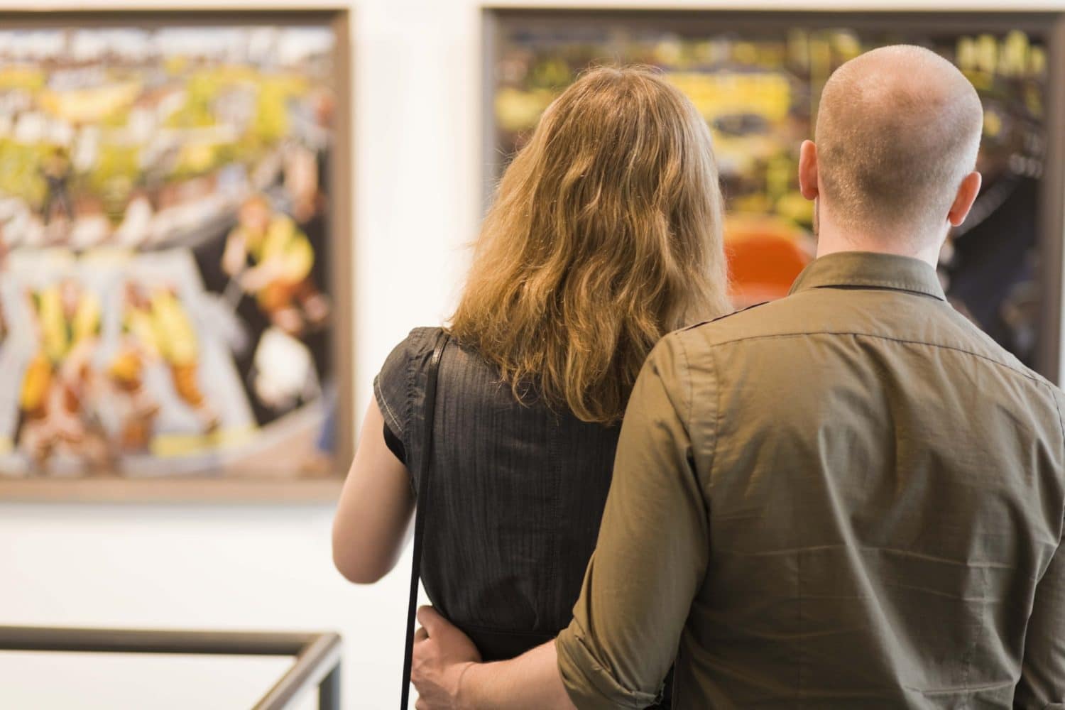 A couple stands close together, admiring artwork in a gallery. A couple stands close together, admiring artwork in a gallery.